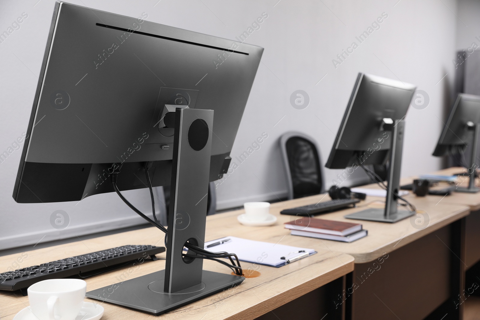 Photo of Open office interior. Modern workplaces with computers near light grey wall