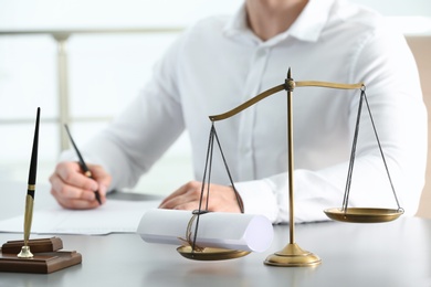 Scales of justice with sealed scroll and blurred view of notary on background