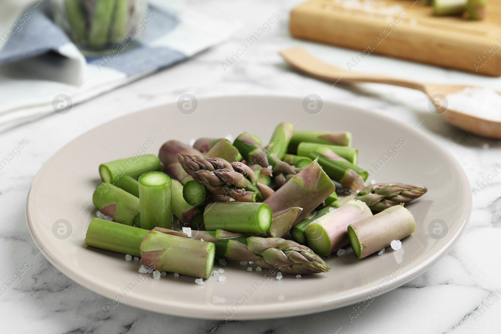 Photo of Fresh raw asparagus on white marble table, closeup