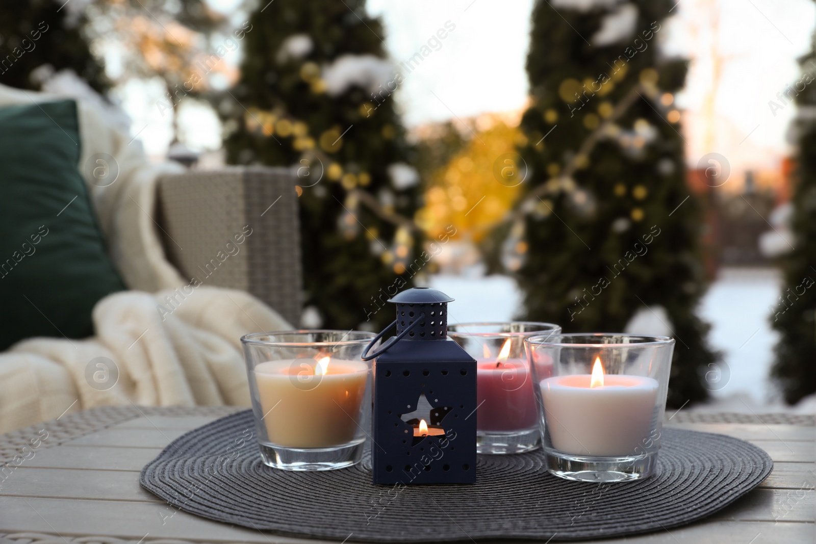 Photo of Beautiful burning candles and lantern on table outdoors. Cozy winter