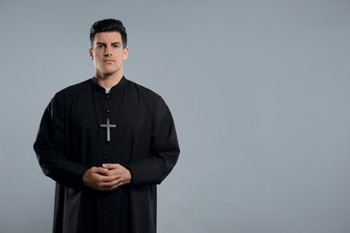 Photo of Priest wearing cassock with clerical collar on grey background. space for text