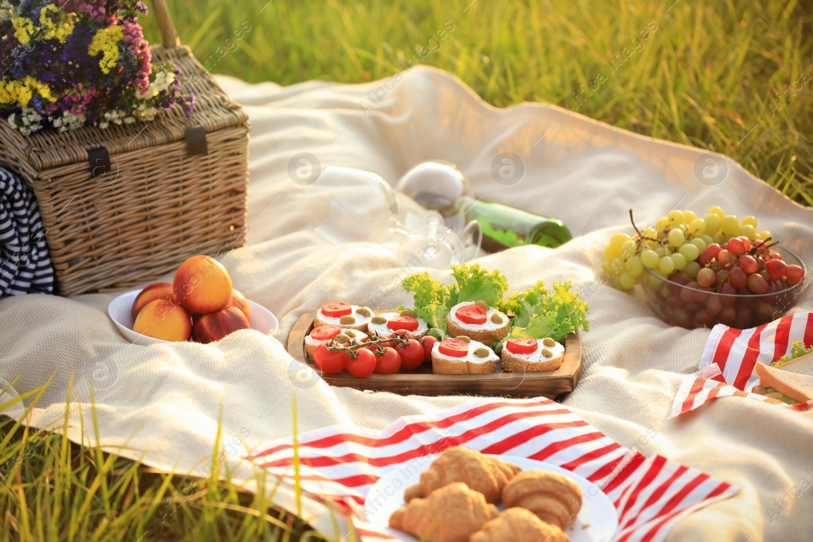 Photo of Picnic blanket with different snacks and wine outdoors