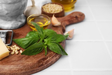 Photo of Different ingredients for cooking tasty pesto sauce on white tiled table, closeup. Space for text