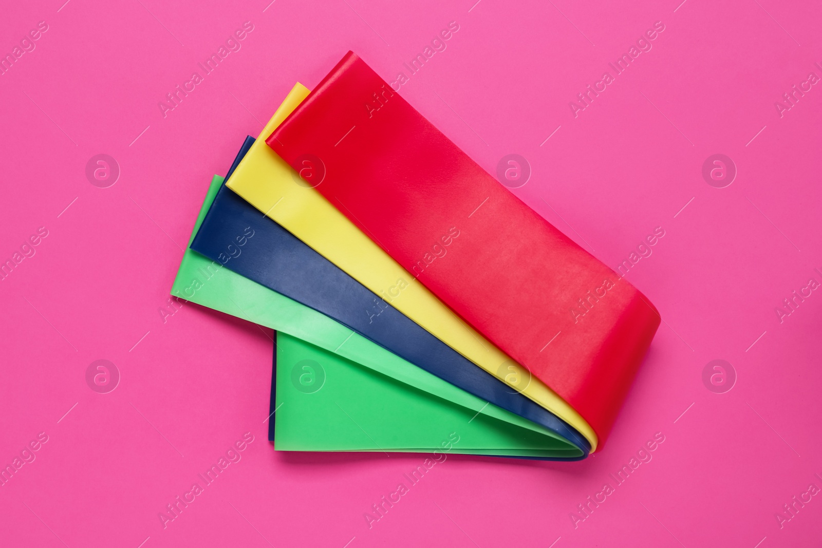 Photo of Set of fitness elastic bands on pink background, flat lay