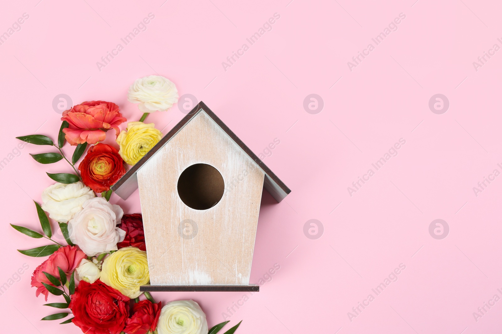 Photo of Stylish bird house and fresh flowers on pink background, flat lay. Space for text