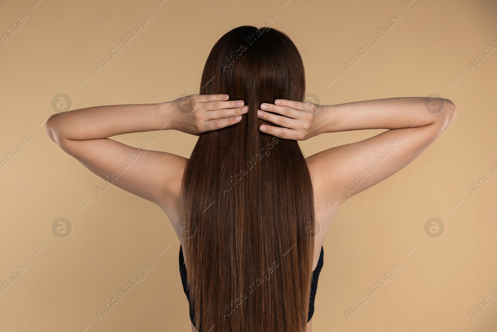 Photo of Young woman with strong healthy hair on beige background, back view