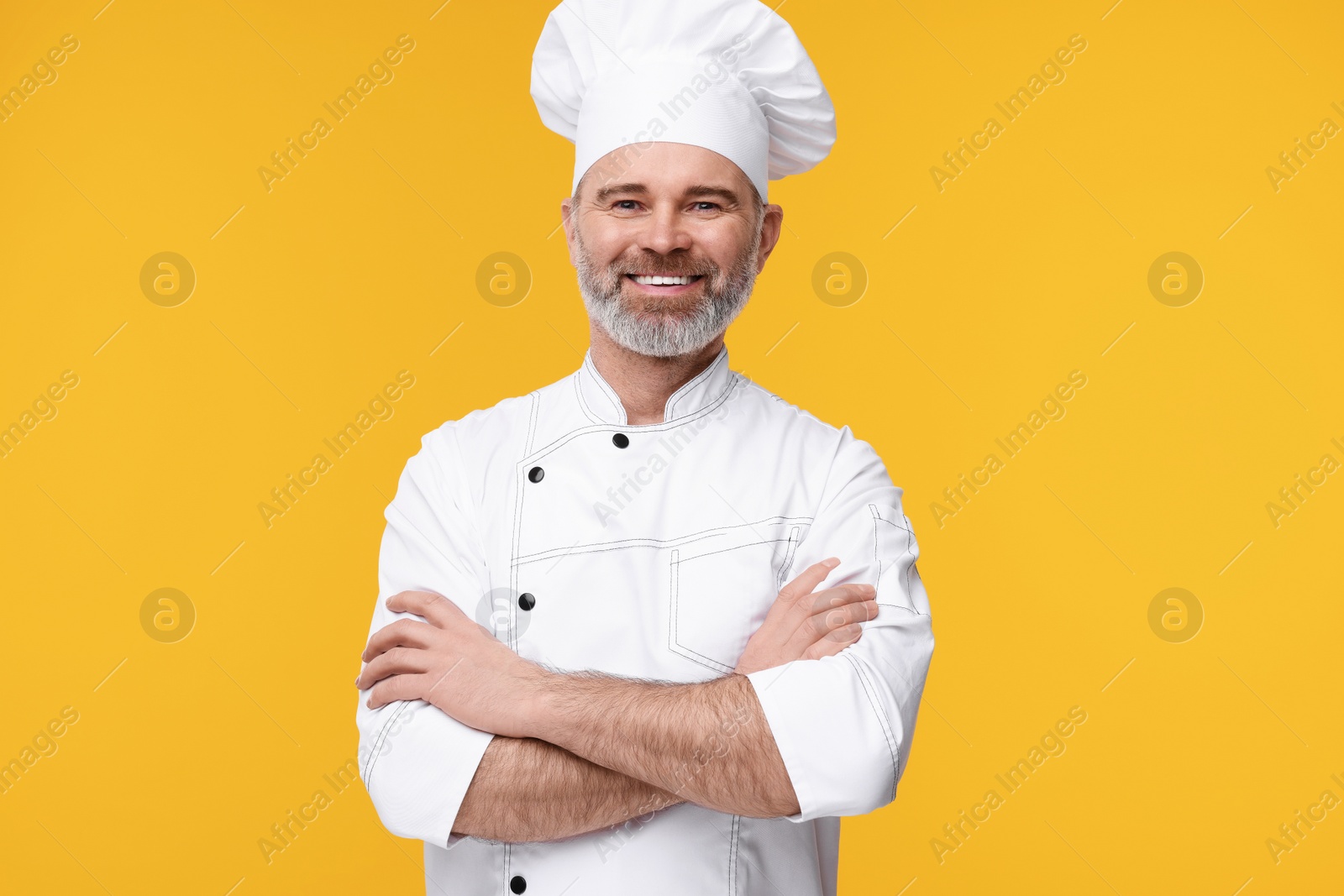 Photo of Happy chef in uniform on orange background
