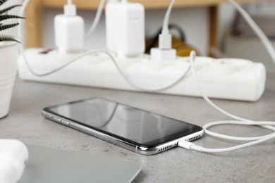 Photo of Smartphone charging with cable on light stone table