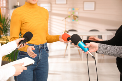 Group of journalists interviewing woman in room, closeup