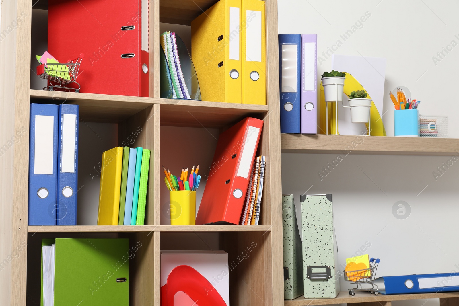 Photo of Colorful binder office folders and other stationery on shelving unit indoors