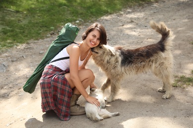 Photo of Young woman playing with stray dogs outdoors. Camping season