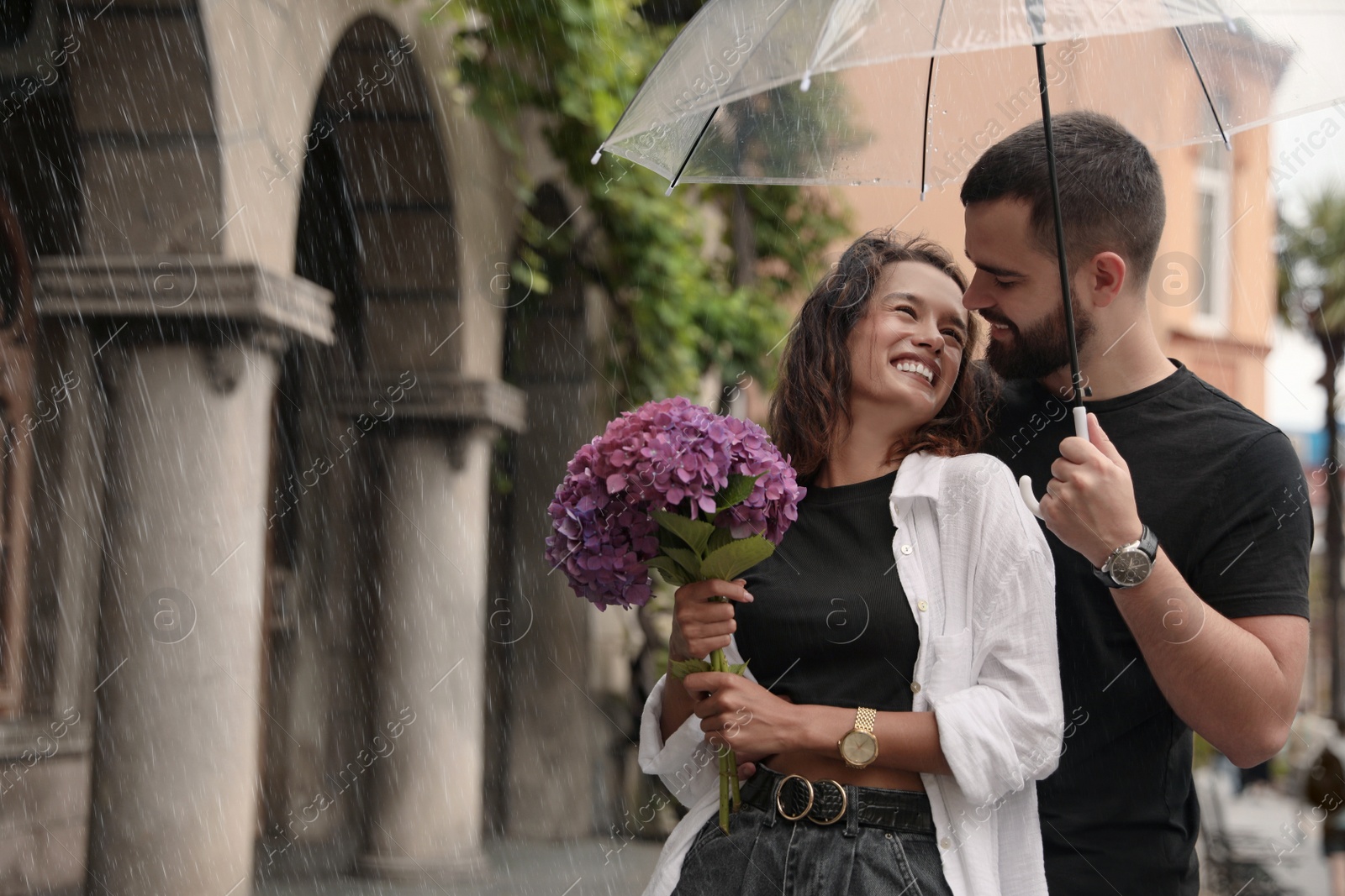 Photo of Young couple with umbrella enjoying time together under rain on city street, space for text