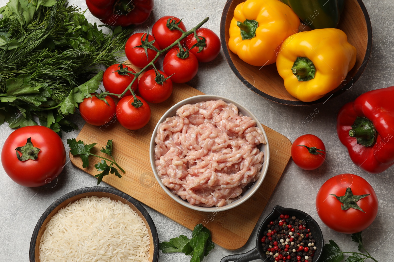 Photo of Making stuffed peppers. Ground meat and other ingredients on grey table, flat lay