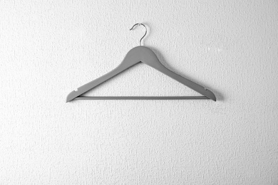 Photo of Empty clothes hanger on light wall. Wardrobe accessory