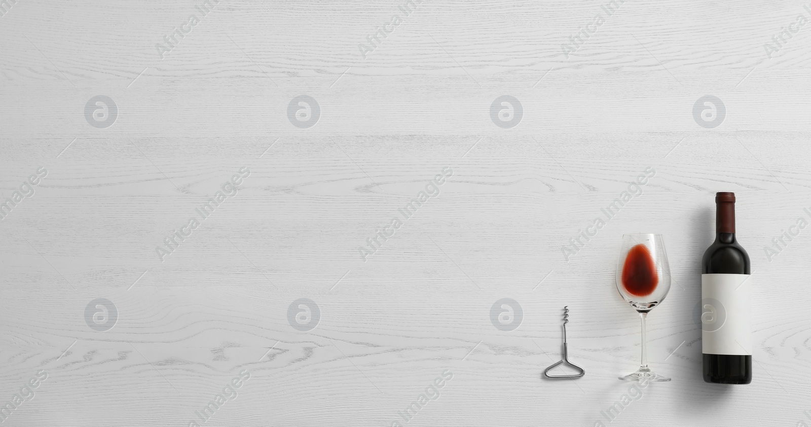 Photo of Flat lay composition with bottle of wine and elegant glass on white wooden background. Space for text