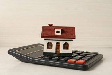 Photo of Mortgage concept. House model and calculator on white wooden table