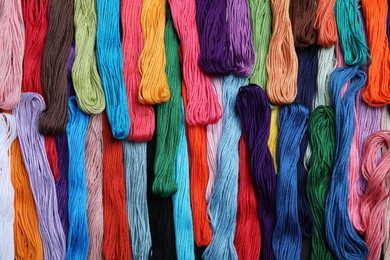 Photo of Different colorful embroidery threads as background, top view