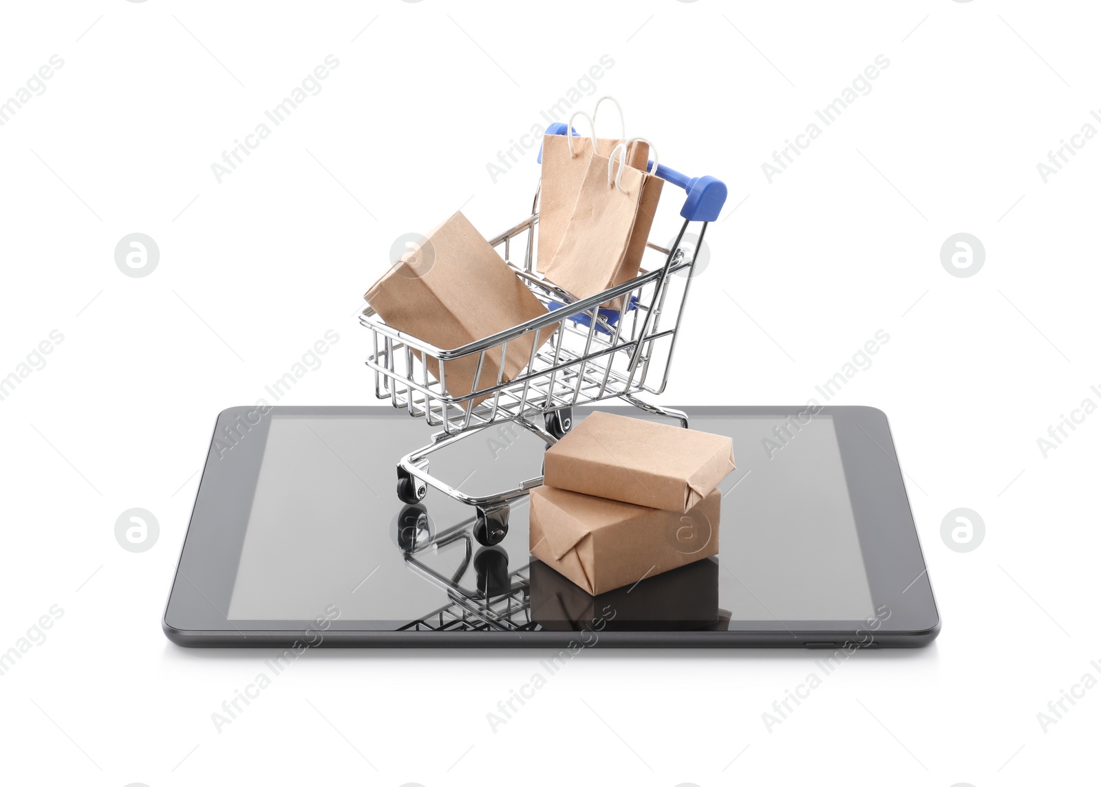 Photo of Small cart with bags and boxes on modern tablet against white background. Internet shopping