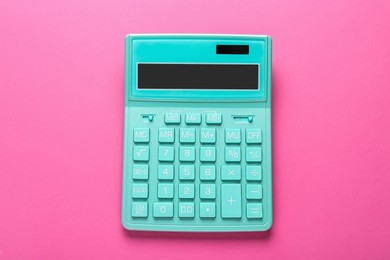 Turquoise calculator on pink background, top view