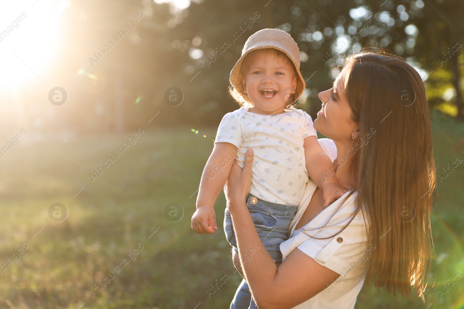 Photo of Happy mother with her cute baby daughter in park on sunny day. Space for text