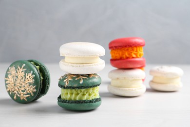 Different decorated Christmas macarons on white table, closeup