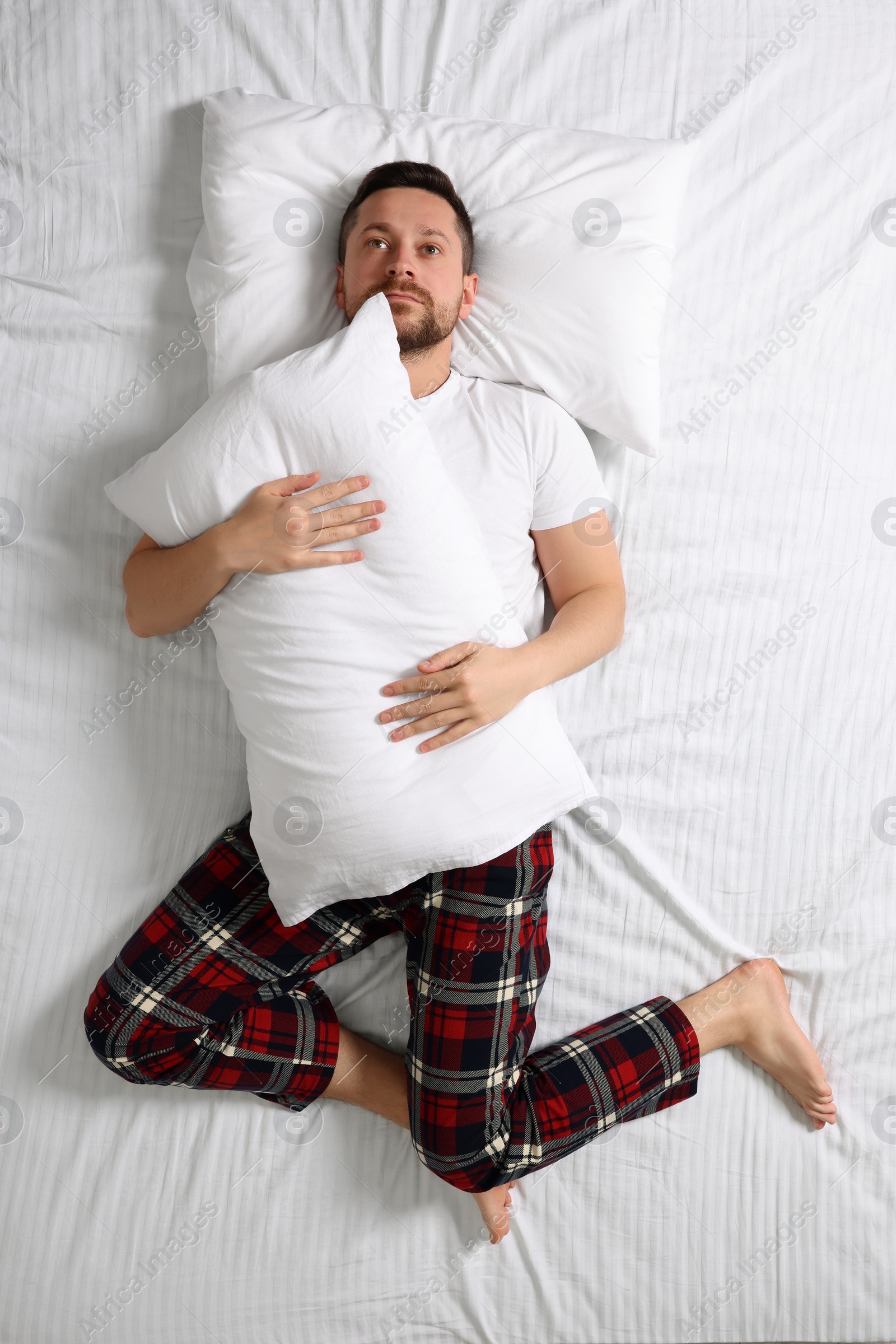 Photo of Man suffering from insomnia on bed, top view