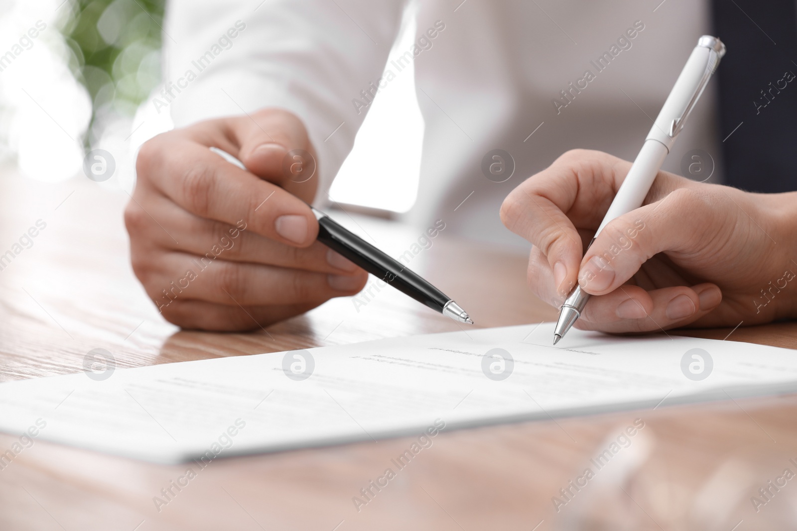 Photo of Businesspeople signing contract at table in office, closeup