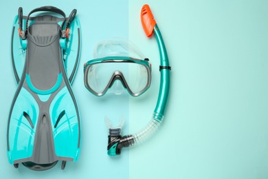 Pair of flippers, snorkel and diving mask on turquoise background, flat lay