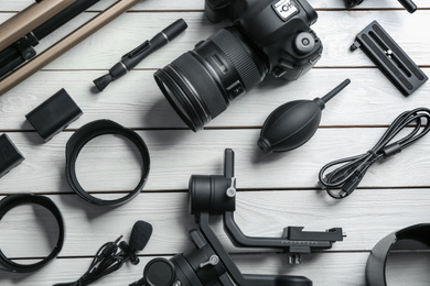 Flat lay composition with camera and video production equipment on white wooden table