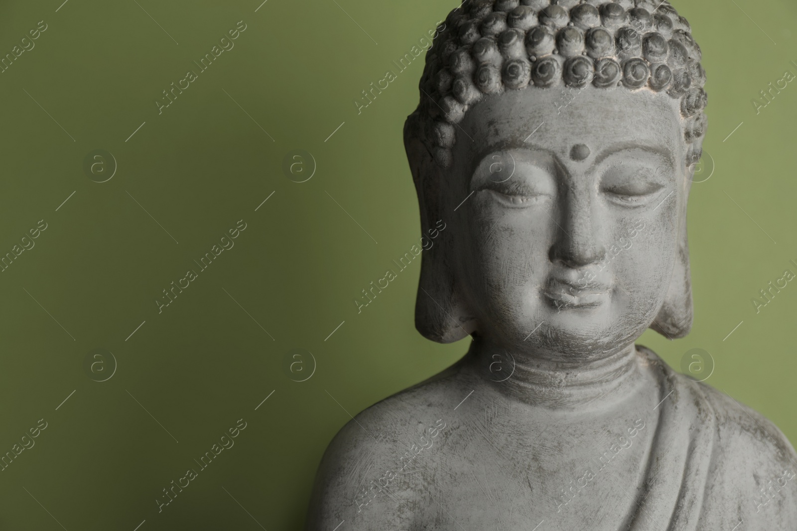 Photo of Beautiful stone Buddha sculpture on green background. Space for text