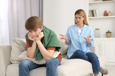 Photo of Teenage son ignoring mother while she scolding him at home