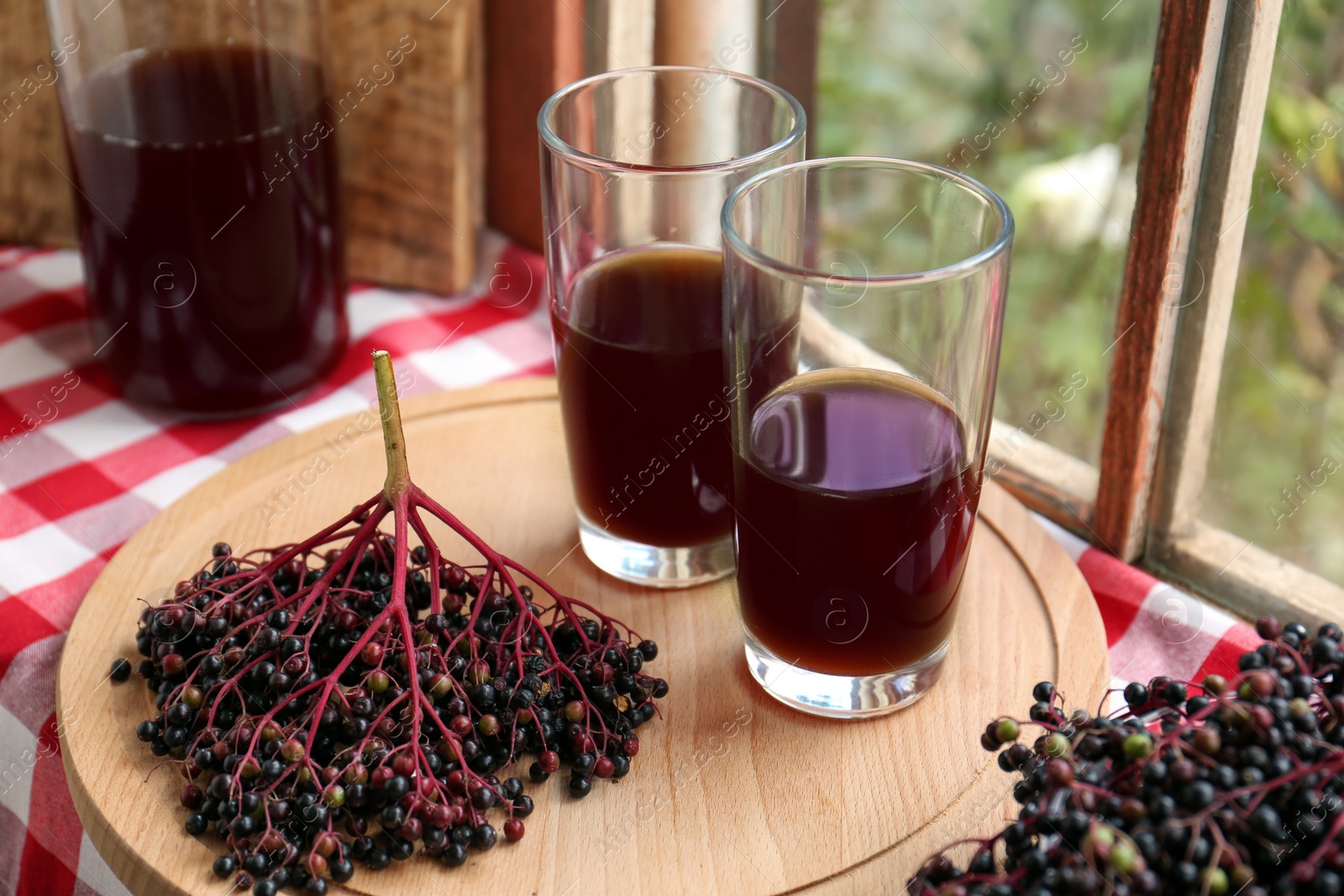 Photo of Elderberry drink and Sambucus berries on table near window