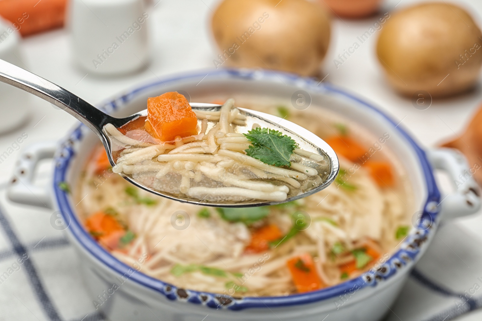 Photo of Spoon with fresh homemade chicken soup on table, closeup