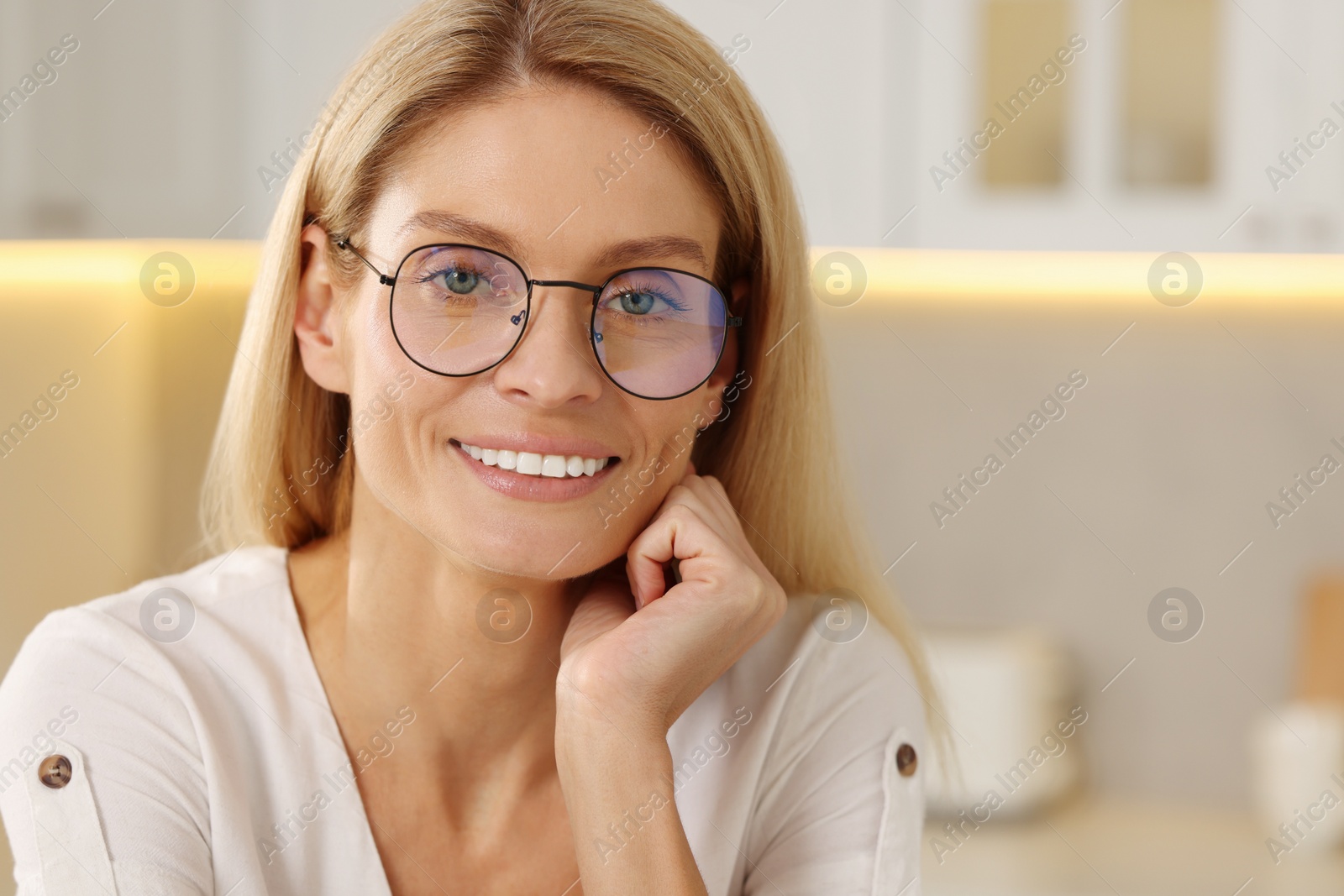 Photo of Portrait of smiling woman with stylish glasses in kitchen. Space for text