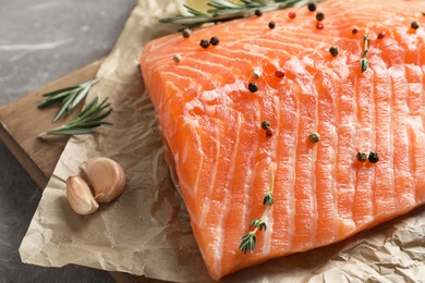 Photo of Wooden board with raw salmon fillet and ingredients for marinade, closeup