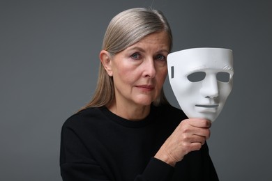 Photo of Multiple personality concept. Woman with mask on gray background