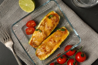 Photo of Flat lay composition with baked stuffed zucchinis served on black table