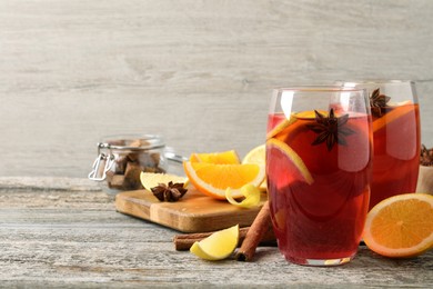 Photo of Aromatic punch drink and ingredients on wooden table. Space for text