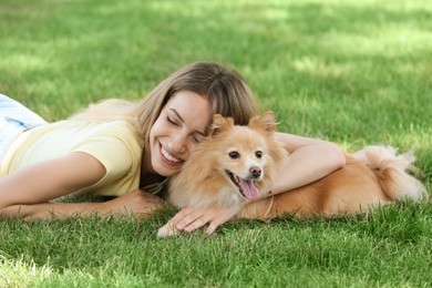 Young woman with her cute dog on green grass in park