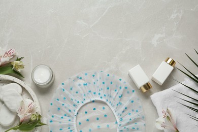 Flat lay composition with shower cap and toiletries on grey marble background. Space for text