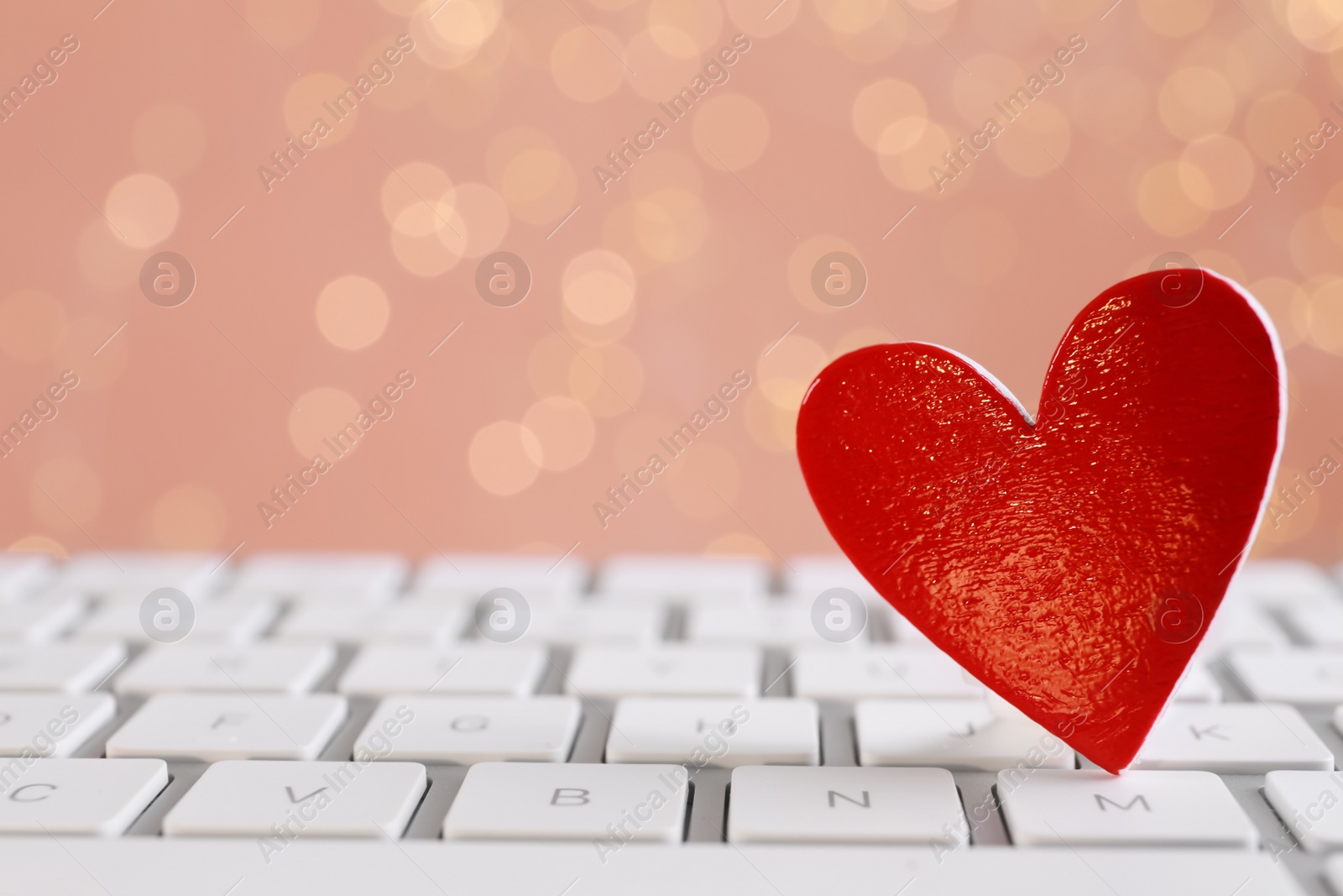 Photo of Red decorative heart on laptop keyboard, closeup. Online dating concept