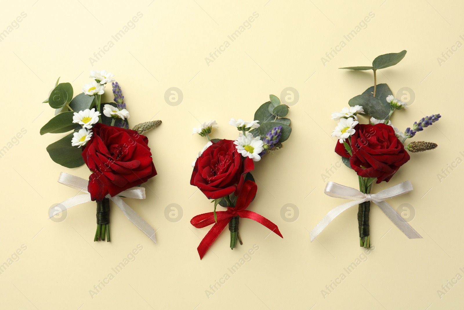 Photo of Many stylish red boutonnieres on beige background, flat lay