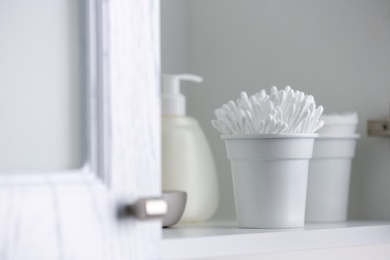 Photo of Container with cotton buds on shelf indoors