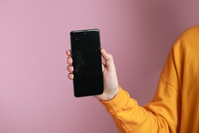 Woman showing damaged smartphone on pink background, closeup. Device repairing