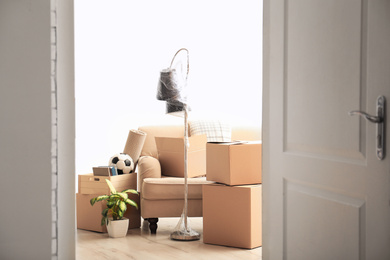 Photo of Cardboard boxes and household stuff in living room. Moving day