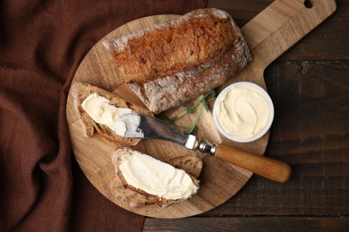 Tasty bread with butter and knife on wooden table, top view