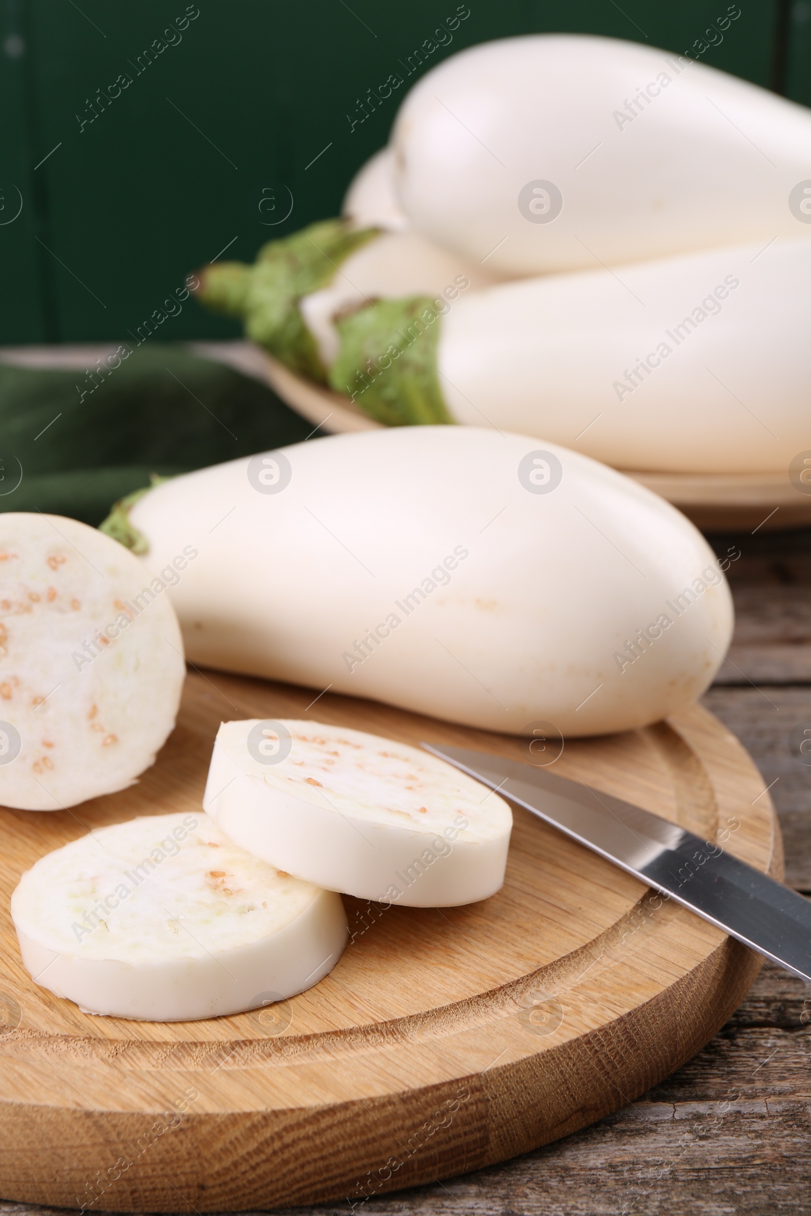 Photo of Board with raw eggplants and knife on wooden table