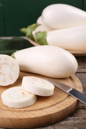 Photo of Board with raw eggplants and knife on wooden table