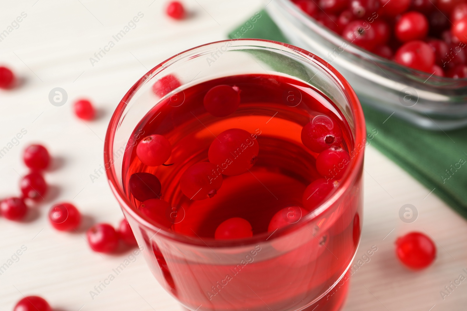 Photo of Tasty cranberry juice in glass and fresh berries on white wooden table, closeup