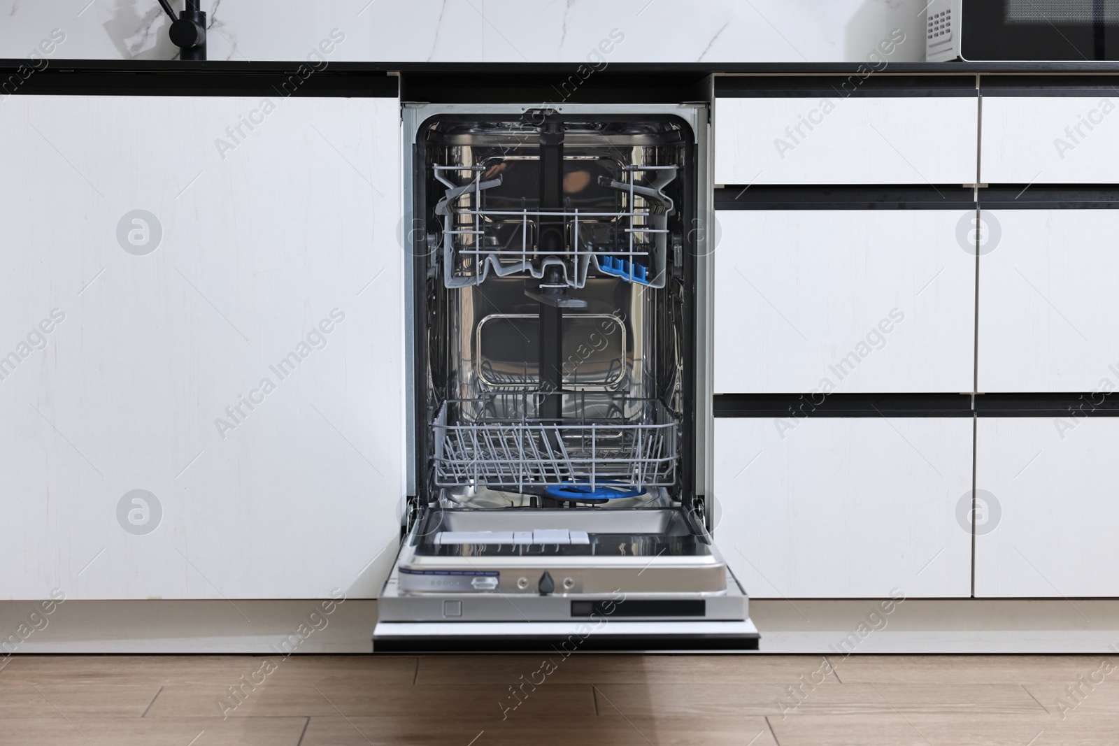 Photo of Open clean empty dishwasher in kitchen. Home appliance